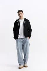 Campera con capucha y cierre frontal, color negro, con bolsillo canguro. Presenta estampado de letras y logo en el pecho.