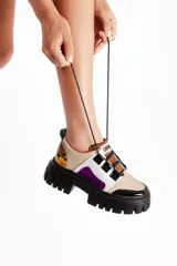 Sneakers de cuero vacuno color beige con detalles en blanco, negro, marrón y violeta. Presenta un cuello acolchado con estampado animal print, cordones negros y suela track negra.