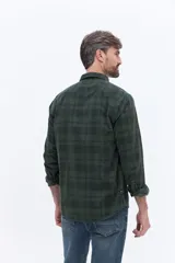 Camisa de manga larga confeccionada en viyela de algodón con diseño a cuadros en tonos verde oscuro. Presenta cuello clásico, cierre frontal con botones y bolsillo aplicado en el pecho.