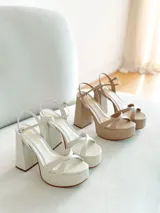 Sandalias de cuero sintético color manteca, con plataforma y tacón bloque. Presentan tiras cruzadas en el empeine y pulsera con hebilla al tobillo.