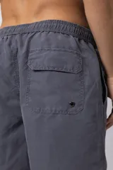 Short de baño de corte relajado en color gris azulado con efecto lavado. Cuenta con cintura elastizada con cordón ajustable, bolsillos laterales y una pequeña etiqueta decorativa en el ruedo.