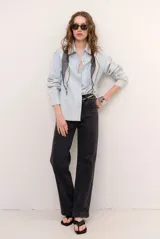 Pantalón de jean color negro, de corte recto y tiro alto, con bolsillos laterales y traseros.