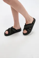 Sandalias negras con tiras cruzadas en el empeine con detalles textiles texturizados y flecos en los bordes. Base plana y cómoda.