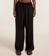 Pantalón de corte holgado y fluido, color negro, con cintura elástica y lazo ajustable. Confeccionado en una mezcla de viscosa y lino.