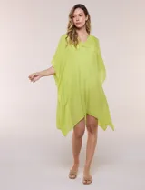 Vestido playero tipo túnica de corte holgado color rosado, confeccionado en tejido semi transparente con textura sutilmente arrugada. Cuenta con escote en V pronunciado, mangas estilo kimono de caída fluida y aberturas laterales en el ruedo irregular.