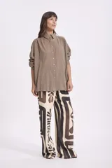 Camisa blanca de manga larga con textura, cuello clásico y botones frontales.