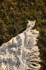 Bufandón triangular tejido en lana merino, con diseño calado y terminaciones con flecos largos en los extremos. Versátil para usar como bufanda o chal.