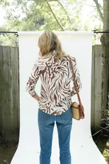 Camisa de fibrana de corte clásico con estampado animal print tipo cebra en tonos chocolate sobre base off-white, mangas largas, cuello camisero y cierre frontal con botones.