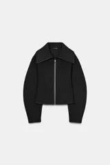 Chaqueta entallada de tejido efecto neopreno en color negro, con cuello solapa amplio, cierre frontal con cremallera y mangas largas abullonadas.