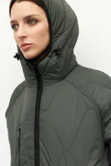 Campera larga oversized color verde militar, de nylon capitoneado, con capucha, tres bolsillos externos y uno interno, puños en las mangas y forro polar.