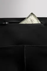 Calzas deportivas largas negras de tejido técnico elástico en cuatro direcciones. Cuentan con cintura elástica ajustable con cordón interior, bolsillos laterales elásticos en la cadera y bolsillo trasero con cierre de cremallera.