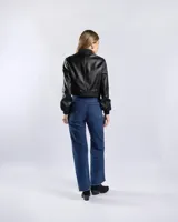 Campera tipo bomber de símil cuero color negro, con cuello, puños y ruedo elásticos. Cuenta con cierre frontal y dos bolsillos diagonales con cierre.