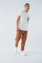 Pantalón cargo verde militar de corte slim, con elástico en la cintura, cordón ajustable, bolsillos cargo con botones y puños elásticos.