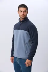 Buzo térmico de polar con diseño bicolor en azul marino y beige. Presenta cuello alto con medio cierre frontal, mangas largas y bolsillos laterales con cierre.