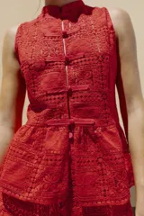 Top sin mangas confeccionado en tejido de guipur con diseño geométrico y floral. Presenta cuello redondo, cierre frontal con botones tipo alamares y bajo con corte evasé.
