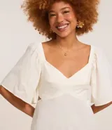 Vestido corto evasé color celeste, con escote en V, mangas cortas amplias, recorte cutout en los laterales de la cintura y volado en el bajo.