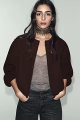 Chaqueta bomber de cuello redondo y manga larga con acabado elástico en puños y ruedo. Presenta cierre frontal con cremallera y bolsillos delanteros de vivo.
