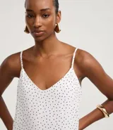 Vestido largo de corte evasé confeccionado en crepé, con escote en V, breteles finos ajustables y detalle de ruedo fruncido. Presenta una estampa clásica de lunares.