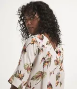 Blusa de viscosa color crudo con estampado de hojas coloridas, escote en V y mangas cortas.