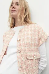Chaleco de tweed color salmón con diseño a cuadros, sin mangas, con bolsillos frontales y botones perlados.