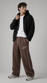Pantalón jogger color marrón tabaco, de corte holgado, con cordón ajustable en la cintura, bolsillos laterales, ribetes blancos y diseño bordado.