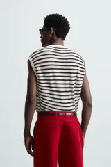 Camiseta sin mangas de punto con cuello redondo, tejido abierto a rayas horizontales negras y blancas, con ribetes en color crema.