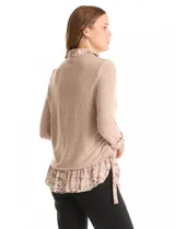 Buzo de tejido fino color beige con diseño de doble capa que simula una camisa debajo. Presenta cuello redondo, mangas largas con puños de gasa estampada en animal print, y ruedo con volado de la misma tela. Incluye detalles de frunces en los laterales.