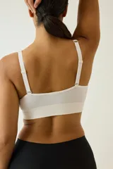 Soutien suave de punto seamless, color beige, con escote en V profundo, tirantes anchos y banda elástica en el bajo. Cuenta con copas con relleno extraíble.