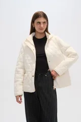Campera acolchada de color blanco con diseño capitoneado en forma de rombos, manga larga, capucha y cierre frontal con botones a presión dorados.