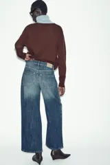 Jeans de tiro bajo, corte recto y largo completo (full length), color azul medio con efecto desgastado y lavado. Modelo de cinco bolsillos con cierre frontal de botones.