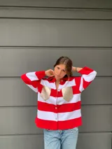 Camisa de manga larga a rayas horizontales rojas y blancas, con cuello camisero, cierre frontal con botones y dos bolsillos dorados en el pecho.