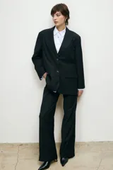 Conjunto sastrero negro, compuesto por un blazer oversize con solapas de muesca, cierre con dos botones y bolsillos con solapa, combinado con un pantalón de vestir de corte recto.