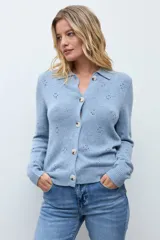 Cardigan de punto color ocre, con diseño calado de pequeños motivos florales, cuello polo y cierre frontal con botones.