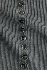 Saco corto de punto acanalado gris oscuro, con cuello redondo, manga larga y cierre frontal abotonado con detalles festoneados.