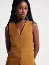 Chaleco sastrero de lino color marrón, con escote en V, cierre frontal con botones y bolsillos laterales simulados.