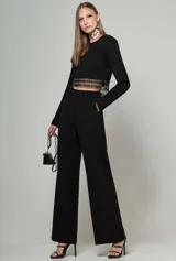 Blusa cropped negra de manga larga con cuello redondo y detalle de bordado metálico en el dobladillo inferior.
