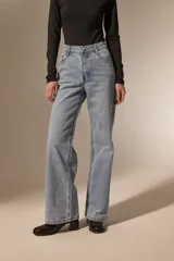 Pantalon de jean de corte recto y tiro medio, con detalle de ojales metálicos a lo largo de la costura lateral externa.