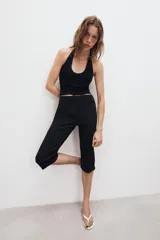 Top de punto color beige, con cuello halter y escote redondo pronunciado, de diseño ajustado al cuerpo.