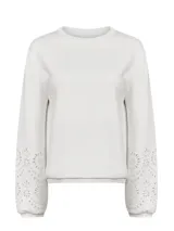 Buzo de algodón orgánico color blanco, con cuello redondo, mangas largas voluminosas y delicados bordados calados en los puños.