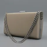 Cartera tipo sobre de fiesta color peltre, con estructura rígida y herrajes metálicos plateados. Incluye correa de cadena doble.