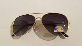 Lentes de sol estilo aviador con montura dorada y lentes polarizadas color gris oscuro.