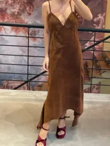 Vestido midi de antílope genuino color chocolate, con breteles finos, escote en V con detalle de pasamanería color cobre y falda de corte irregular.