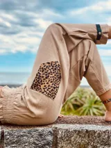 Pantalón de jogging color beige con puños elásticos, parche de animal print en la rodilla y detalle de tira con hebilla en el tobillo.