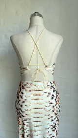 Vestido midi con estampado de piel de serpiente en tonos beige y marrón. Diseño con top halter y falda tubo con abertura lateral.