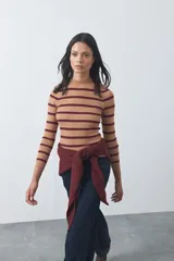 Polera de tejido rib con diseño a rayas horizontales en tonos beige y bordó, de cuello alto y manga larga, con calce ajustado al cuerpo.