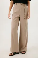 Pantalón de vestir color beige, de corte palazzo y tiro alto. Incluye cinturón de cadena plateada.