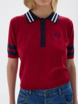 Remera tejida tipo polo, color rojo, con cuello azul marino y rayas blancas. Tiene botones frontales, largo cropped y mangas cortas con franjas azules.
