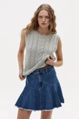 Chaleco de punto color gris melange, con cuello redondo, sisa amplia y largo a la cadera. Presenta un diseño de ochos tradicionales.