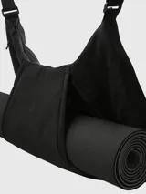 Bolso tipo hobo de diseño funcional, color negro, con compartimento especial para transportar mat de yoga mediante cierres laterales. Confeccionado en poliéster, cuenta con correa de hombro integrada y logo minimalista en el frente.