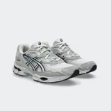 Championes Asics modelo Gel Nyc, en color blanco con detalles en gris claro y azul marino. Confeccionados con malla transpirable y superposiciones sintéticas, con tecnología GEL en la suela para mayor comodidad.